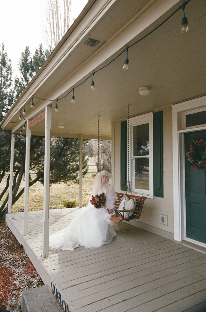 Bride sits on the front porch swing at Long Hollow Ranch